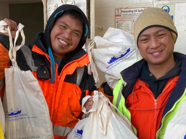 Seemänner mit Päckchen, die sie bei einer Weihnachtsaktion der DMG erhielten.