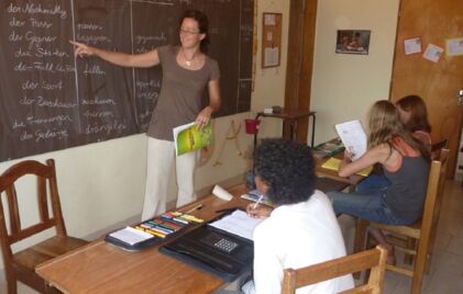 Eine Lehrerin bringt drei Kindern die Grundlagen der deutschen Sprache bei.
